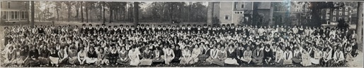 The entire student body, faculty, and staff in Fall of 1923 sitting on a lawn with buildings in the background.