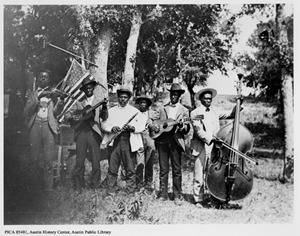 A group of African-American musicians from the 19th century (black and white photo) with an American flag.