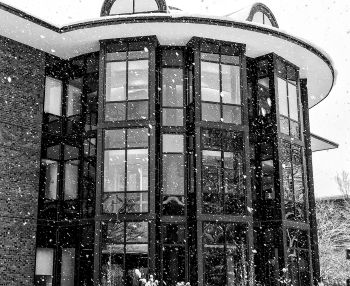 A black and white exterior photo of the library when it is snowing.